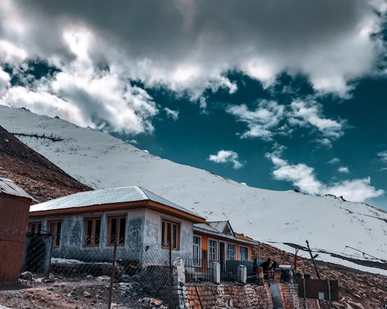 brown and white concrete house under white clouds and blue sky during daytime