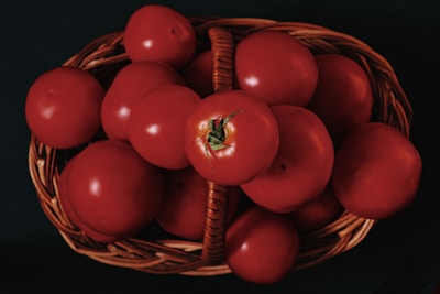 A basket filled with ripe pomegranates and bright red tomatoes.