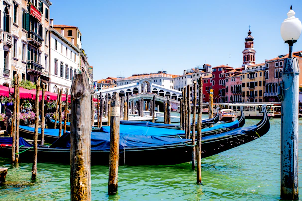 Colorful trajineras floating on Xochimilco canals surrounded by lush greenery under a bright sky.