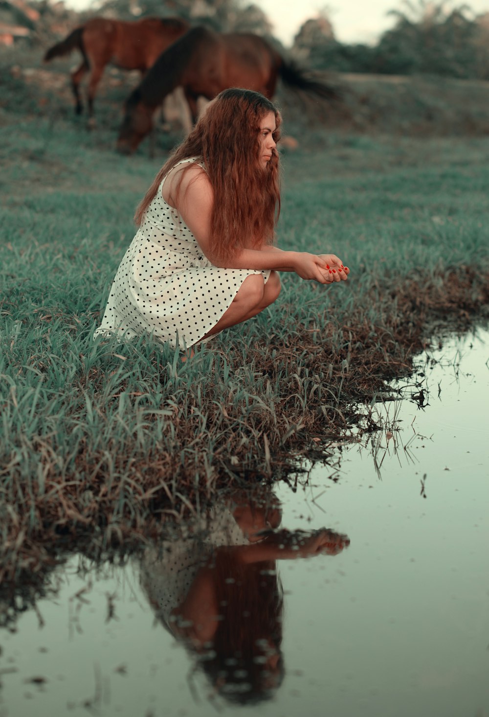 woman in white and black polka dot dress standing on green grass field during daytime