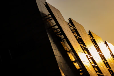 Modern minimalist building facade in deep shadows accented by warm golden light.