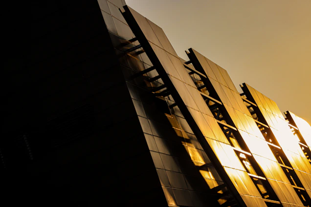 Modern electrical installation team working on a sleek building facade at sunset.