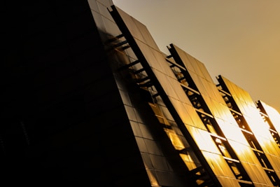 Elegant modern luxury residential building exterior with black and gold accents at sunset.