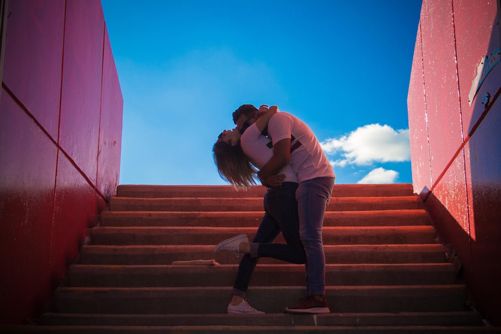 man and woman kissing on the stairs