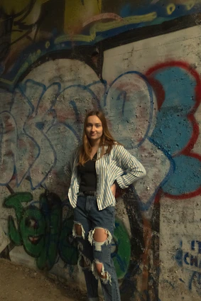 A woman in a trendy urban outfit standing near a graffiti wall, showcasing Code of Wear's design.