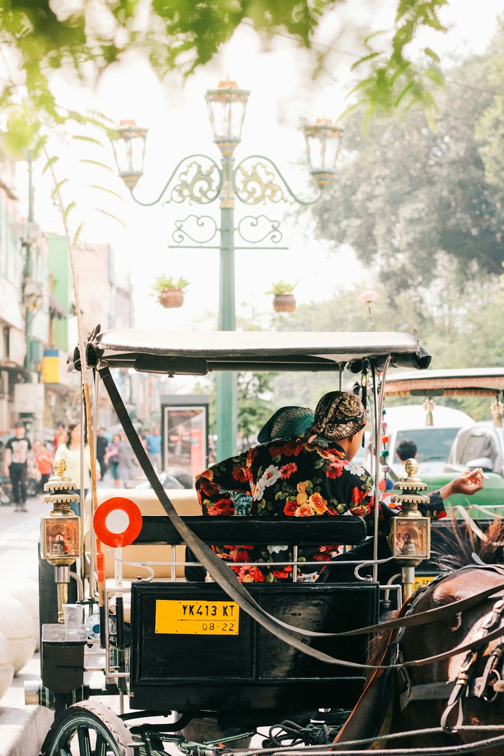 man in black and red floral jacket riding on black and brown auto rickshaw during daytime