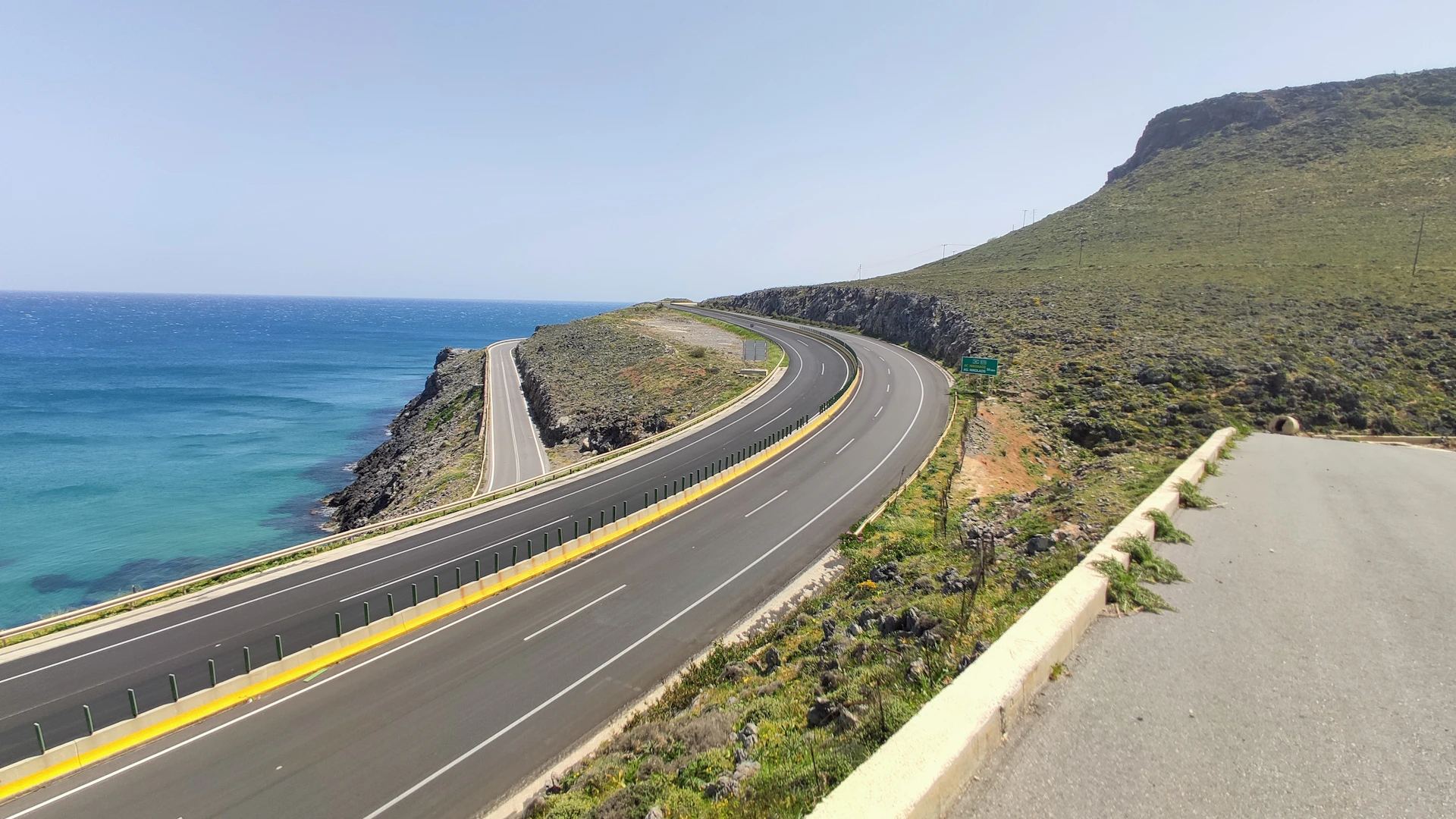 The Jaecoo J7 cruising along a coastal highway, waves crashing nearby and a clear blue sky stretching overhead.