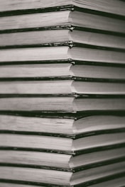grayscale photo of books on wooden surface