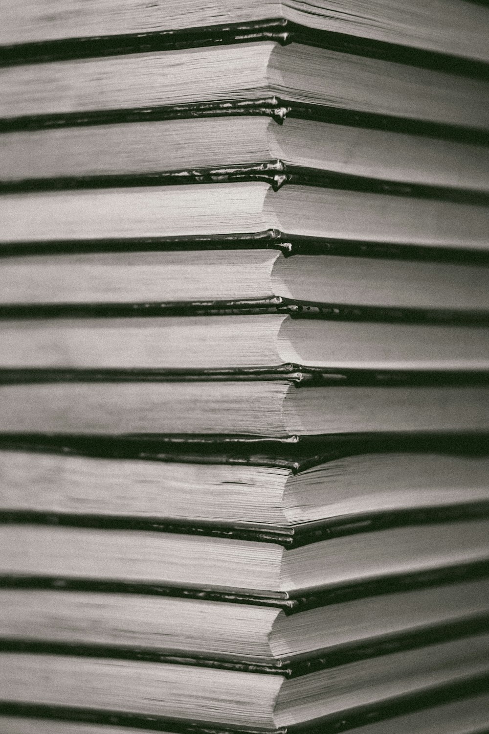 grayscale photo of books on wooden surface