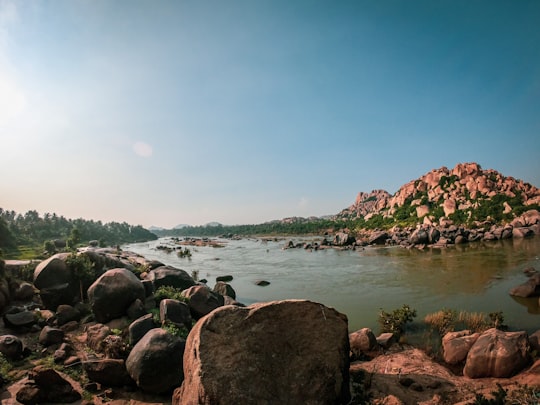 brown rocks near body of water during daytime in Hampi India