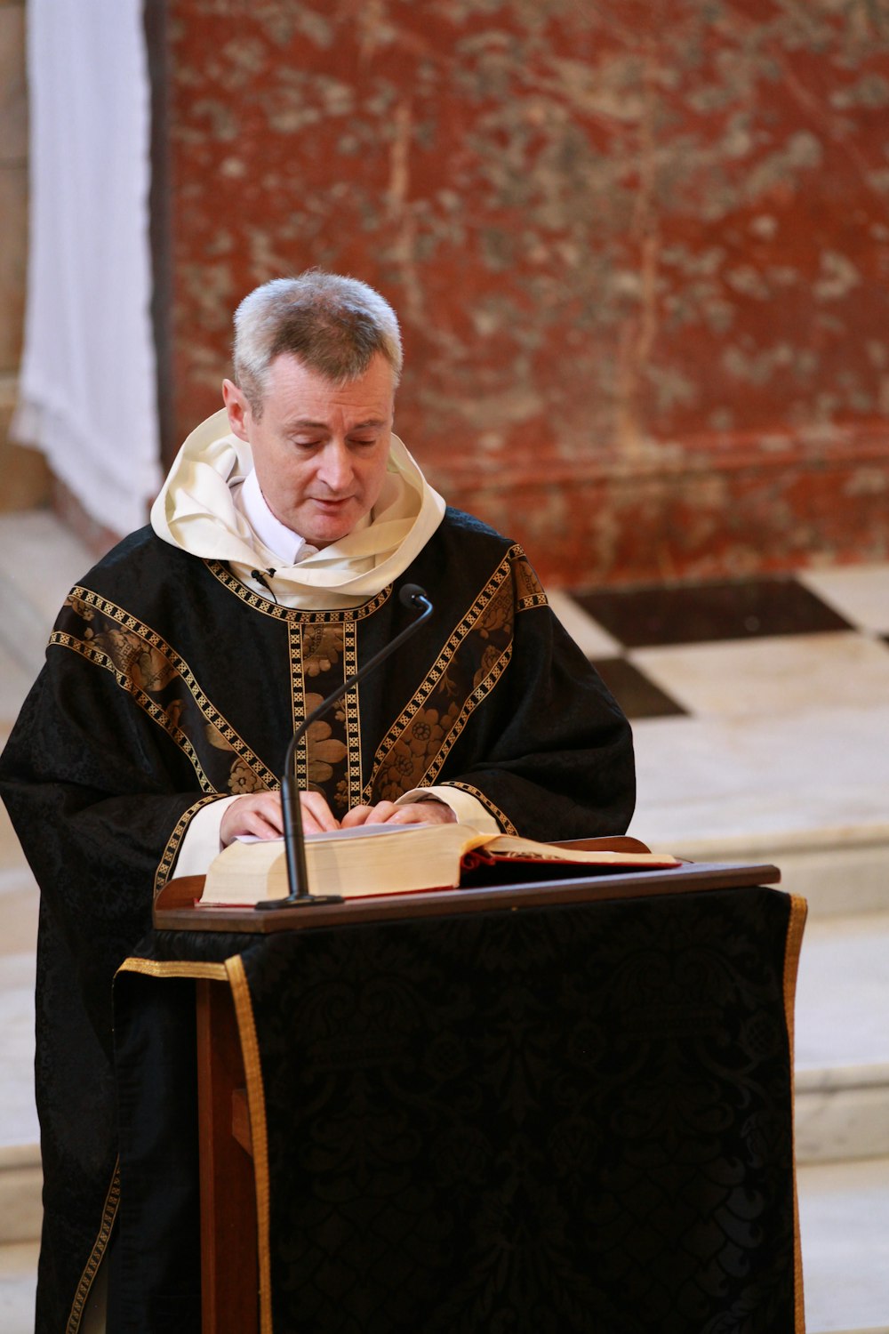 man in black and white robe sitting on brown wooden bench