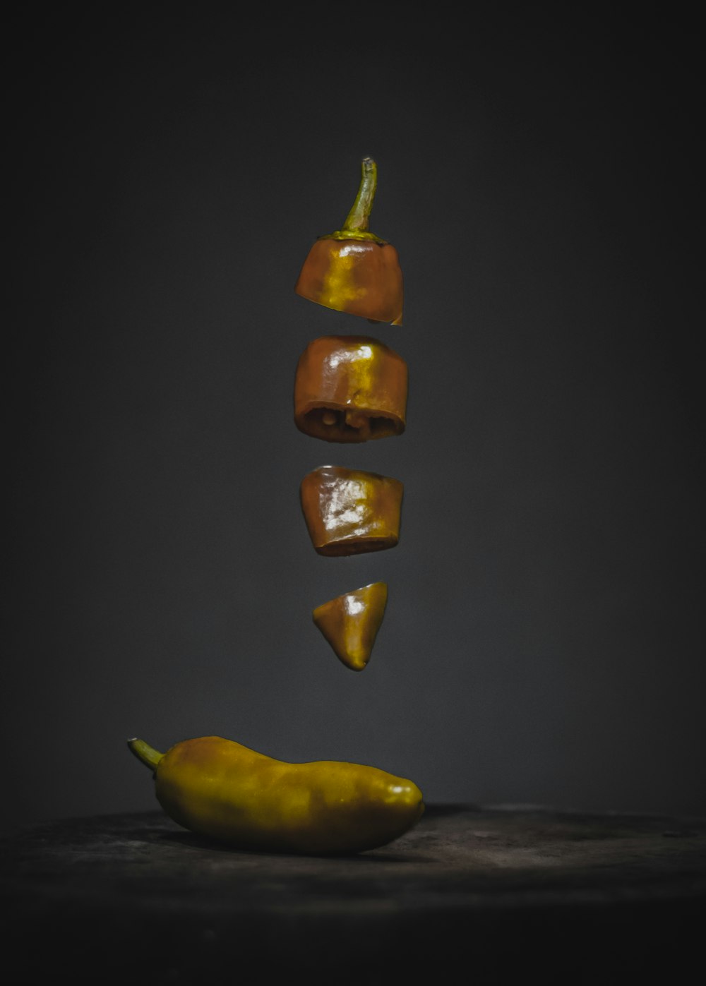 a yellow pepper falling into a pile of peppers