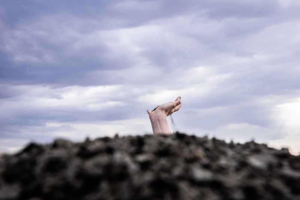 person raising his right hand under blue sky during daytime