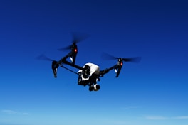 black and white drone flying under blue sky during daytime