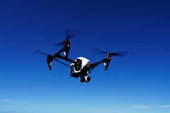 black and white drone flying under blue sky during daytime