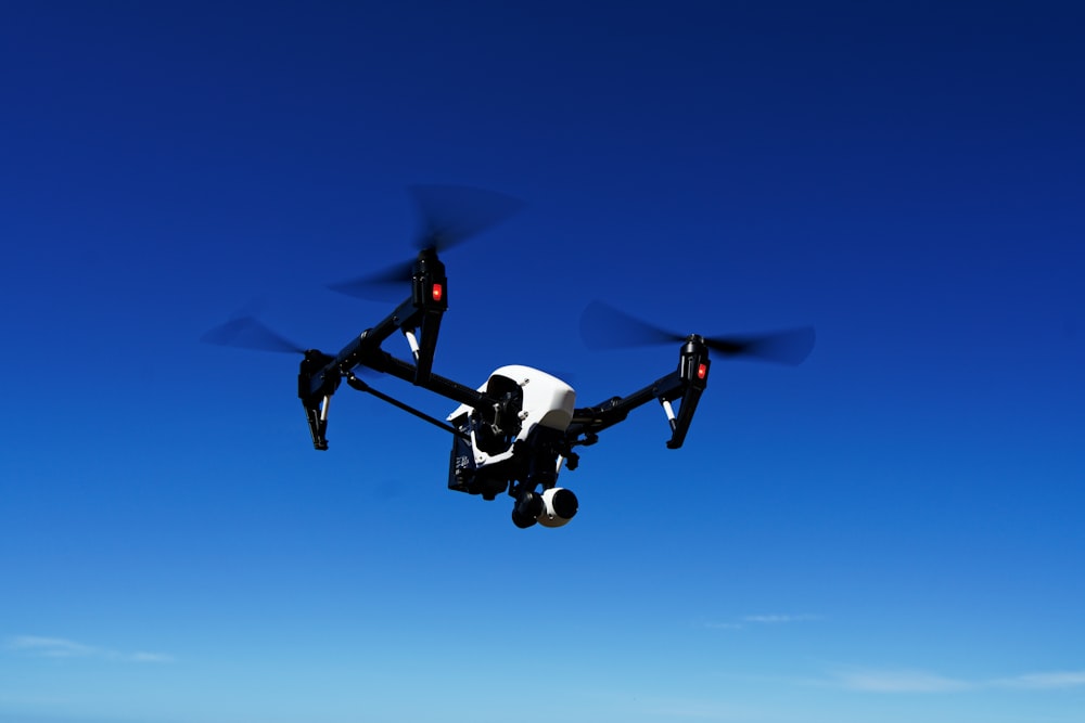 Schwarz-Weiß-Drohne, die tagsüber unter blauem Himmel fliegt