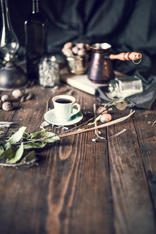 A rustic wooden table displaying traditional Mezopotamian spices and Menengiç coffee cups close up