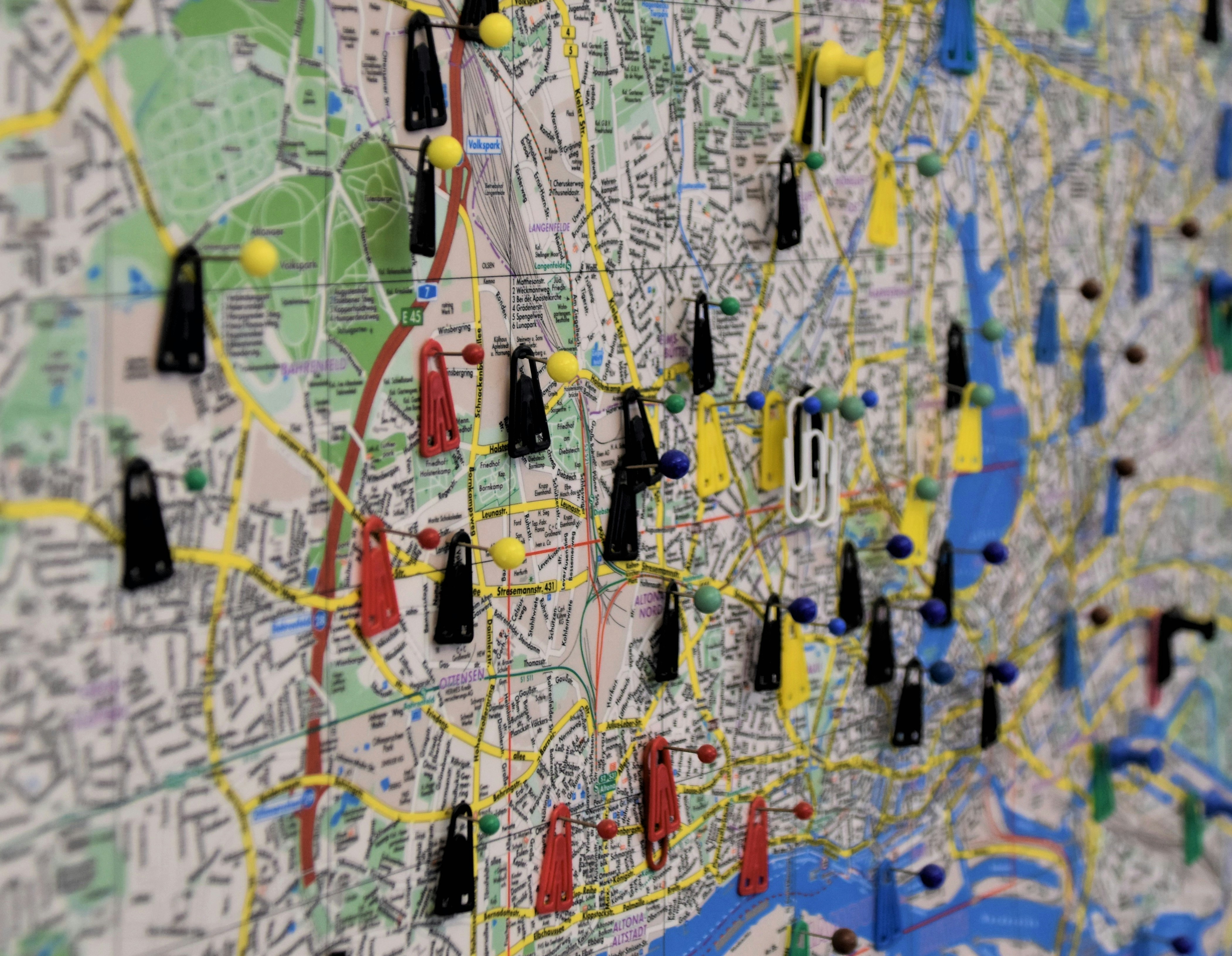 A picture of a city map with several map pins and red and black tags.  
