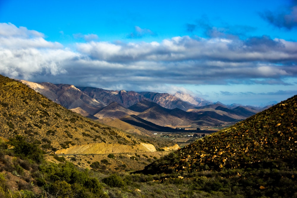 green and brown mountains under white clouds and blue sky during daytime