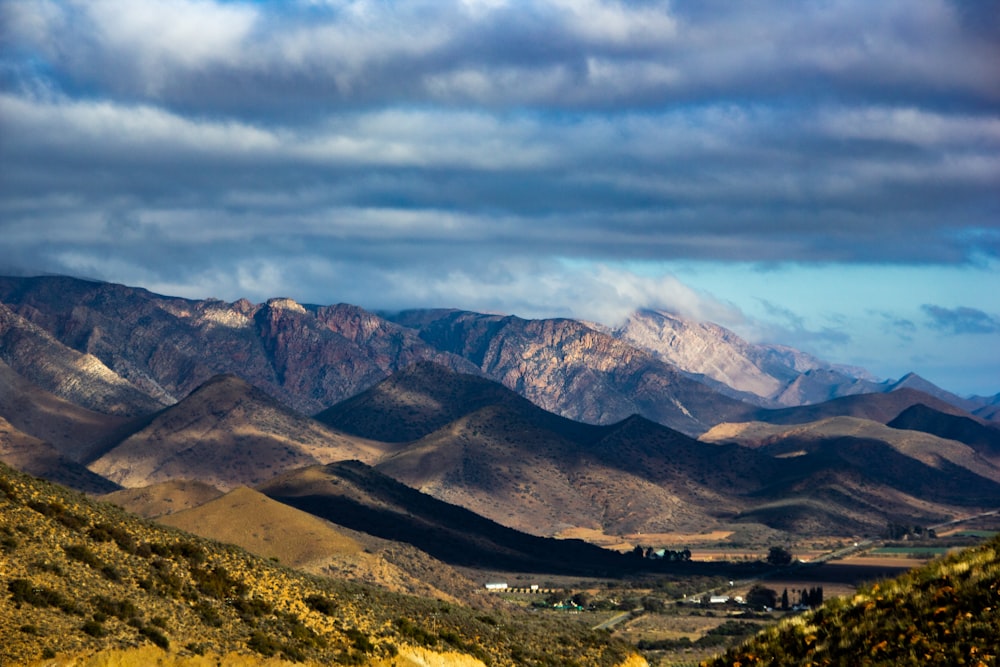 brown and green mountains under white clouds and blue sky during daytime