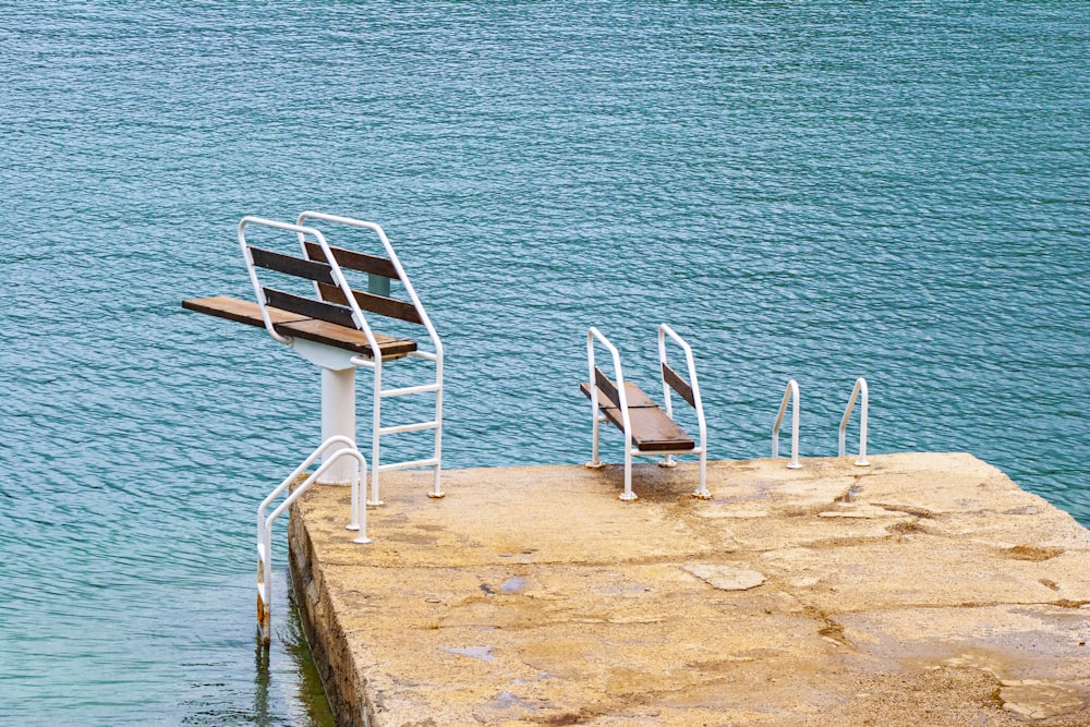 white wooden chair on brown sand near body of water during daytime