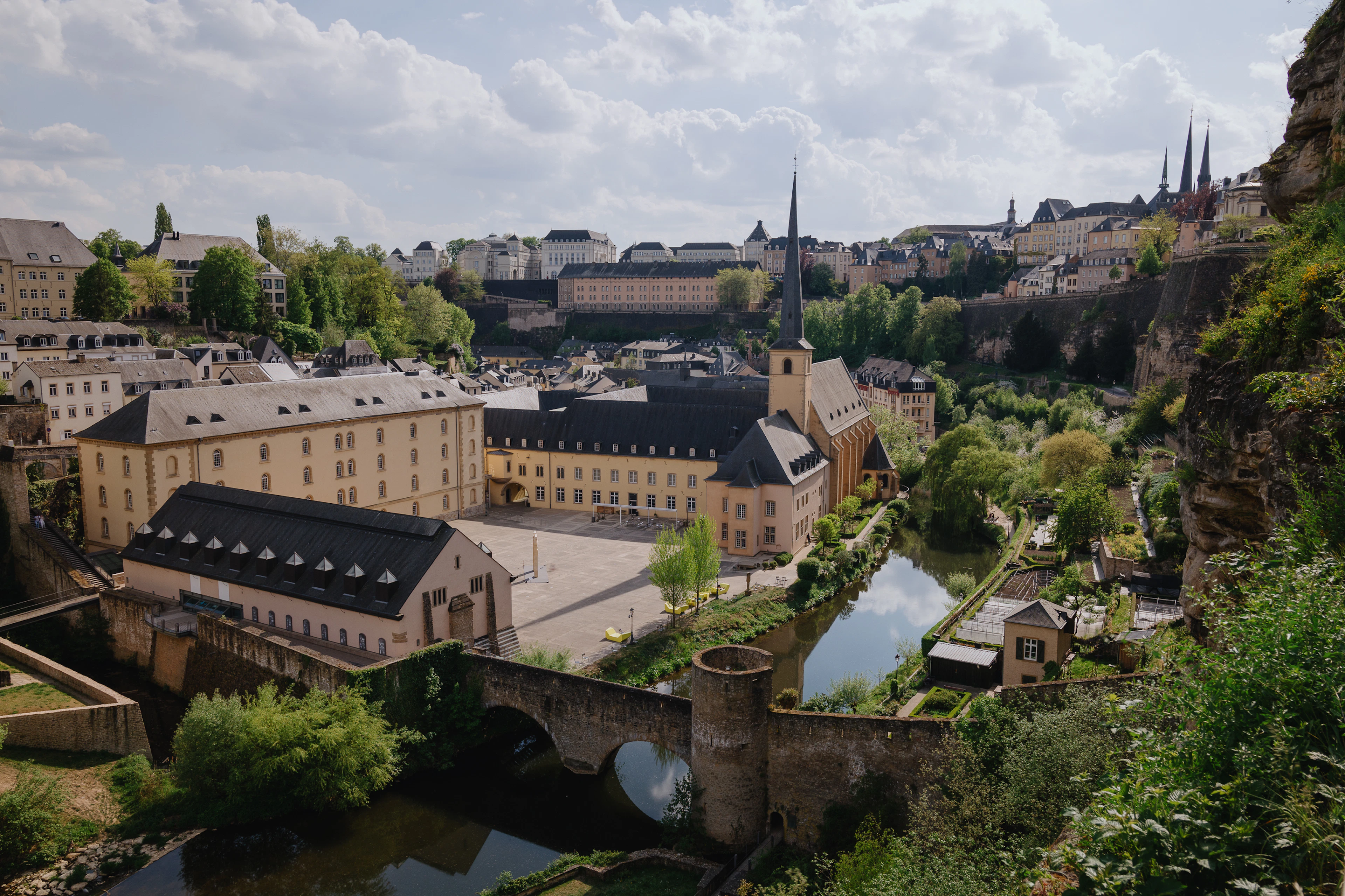 The Neumunster Abbey complex and an old stone bridge over the Alzette in the Grund, below the cliff-top old town of Luxembourg City