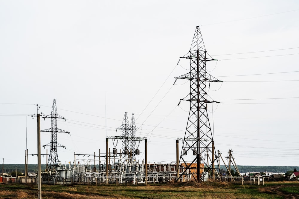 torres elétricas pretas sob o céu branco durante o dia