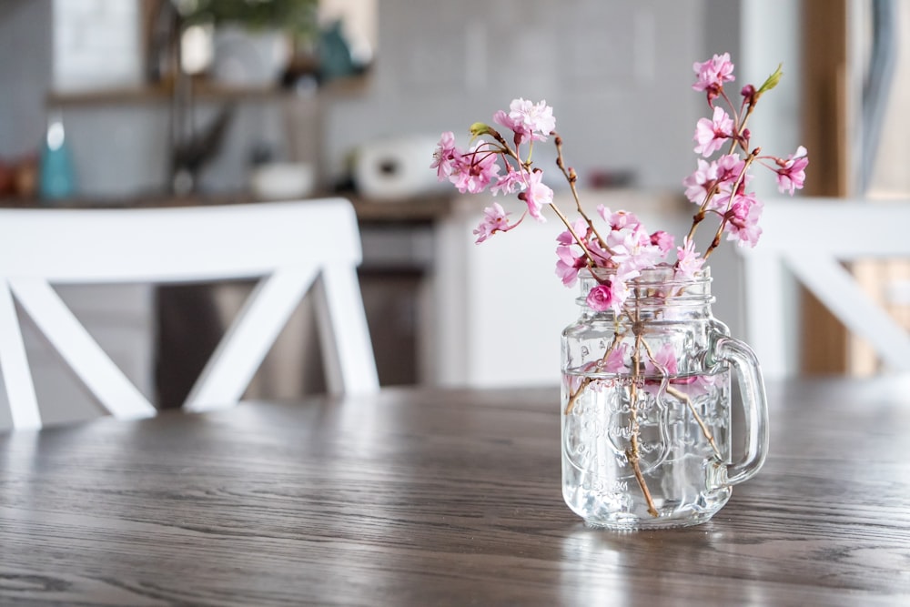 pink flowers in clear glass vase on brown wooden table