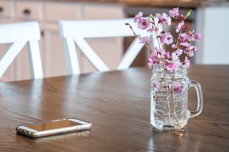 A close-up of a pastel pink phone case with delicate floral patterns resting on a wooden table.