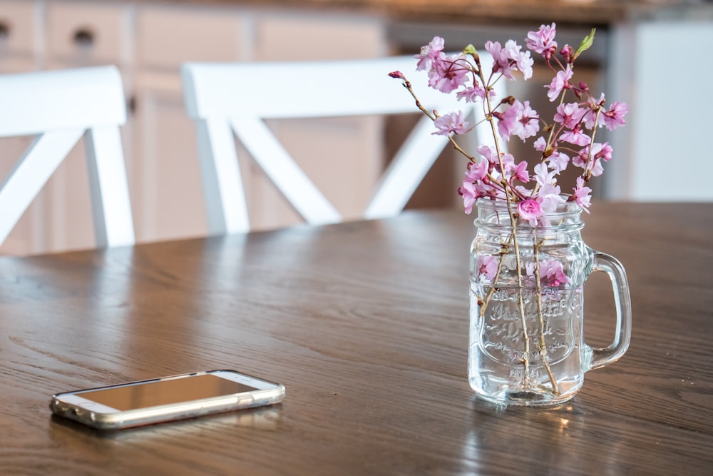 pink flowers in clear glass vase on brown wooden table