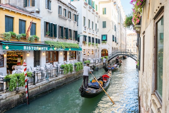 people riding on boat on river between buildings during daytime in Raffaele Italy