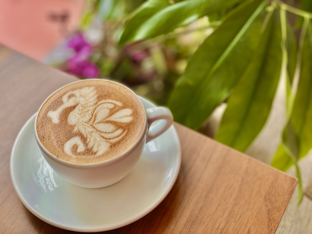 white ceramic cup with cappuccino on white ceramic saucer