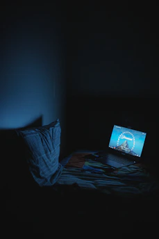 A filmmaker reviewing their film on a laptop in a cozy, dimly lit room.