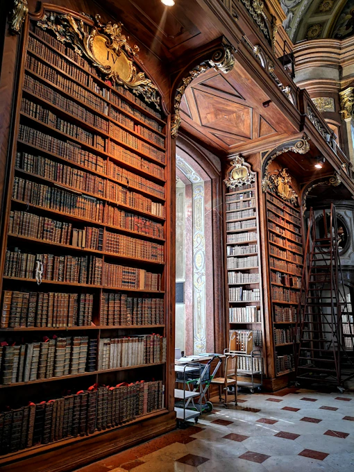 A majestic ancient library with towering black shelves adorned with golden books and a feather pen resting on an open scroll.