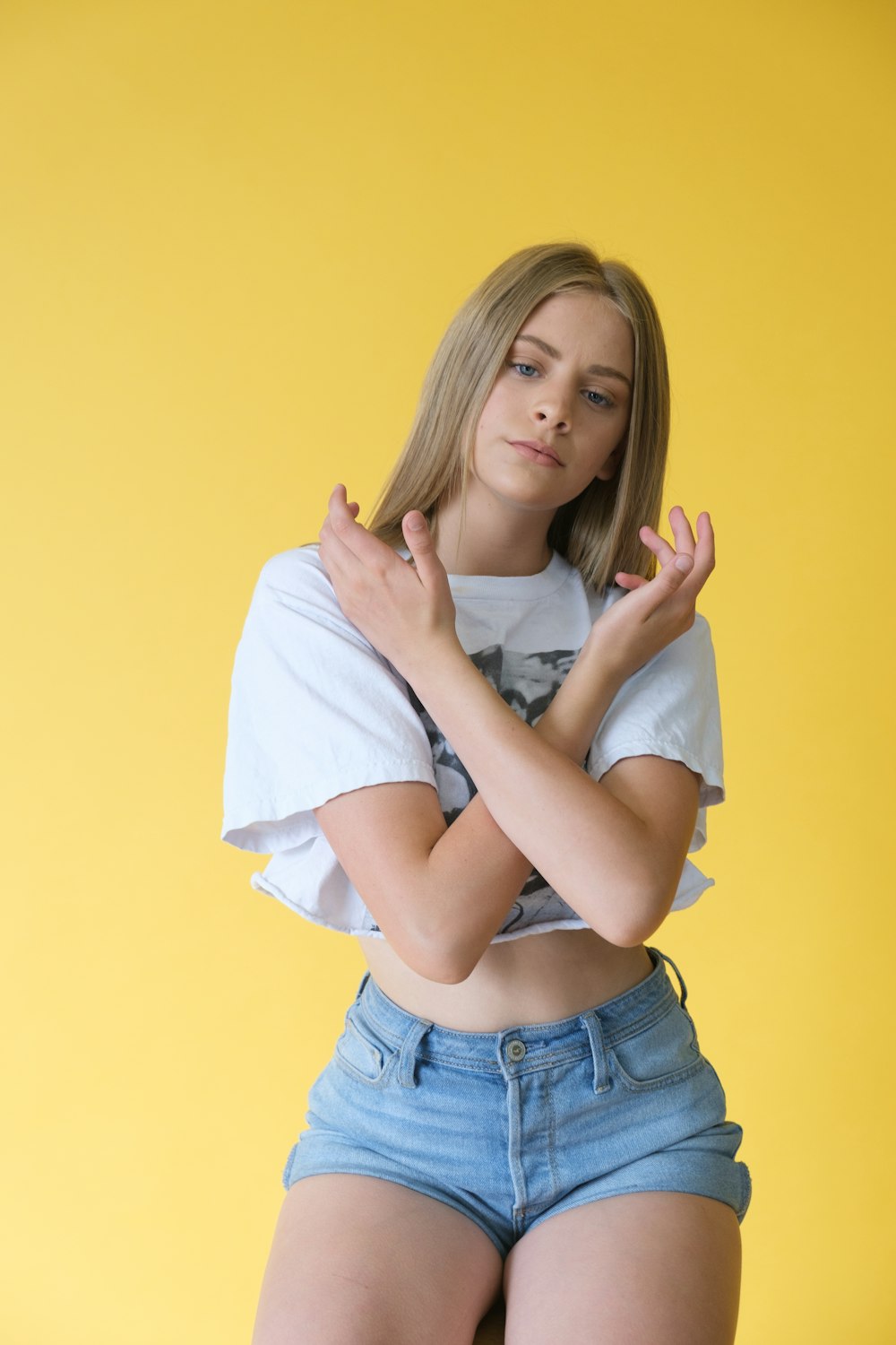 woman in white shirt and blue denim shorts holding white textile