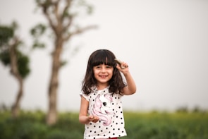 A young girl proudly holding up a handmade craft with a big grin on her face.