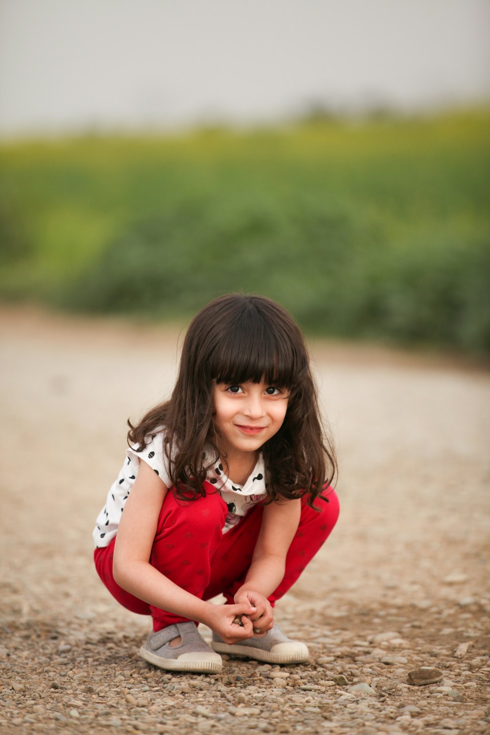 girl in red dress sitting on sand during daytime