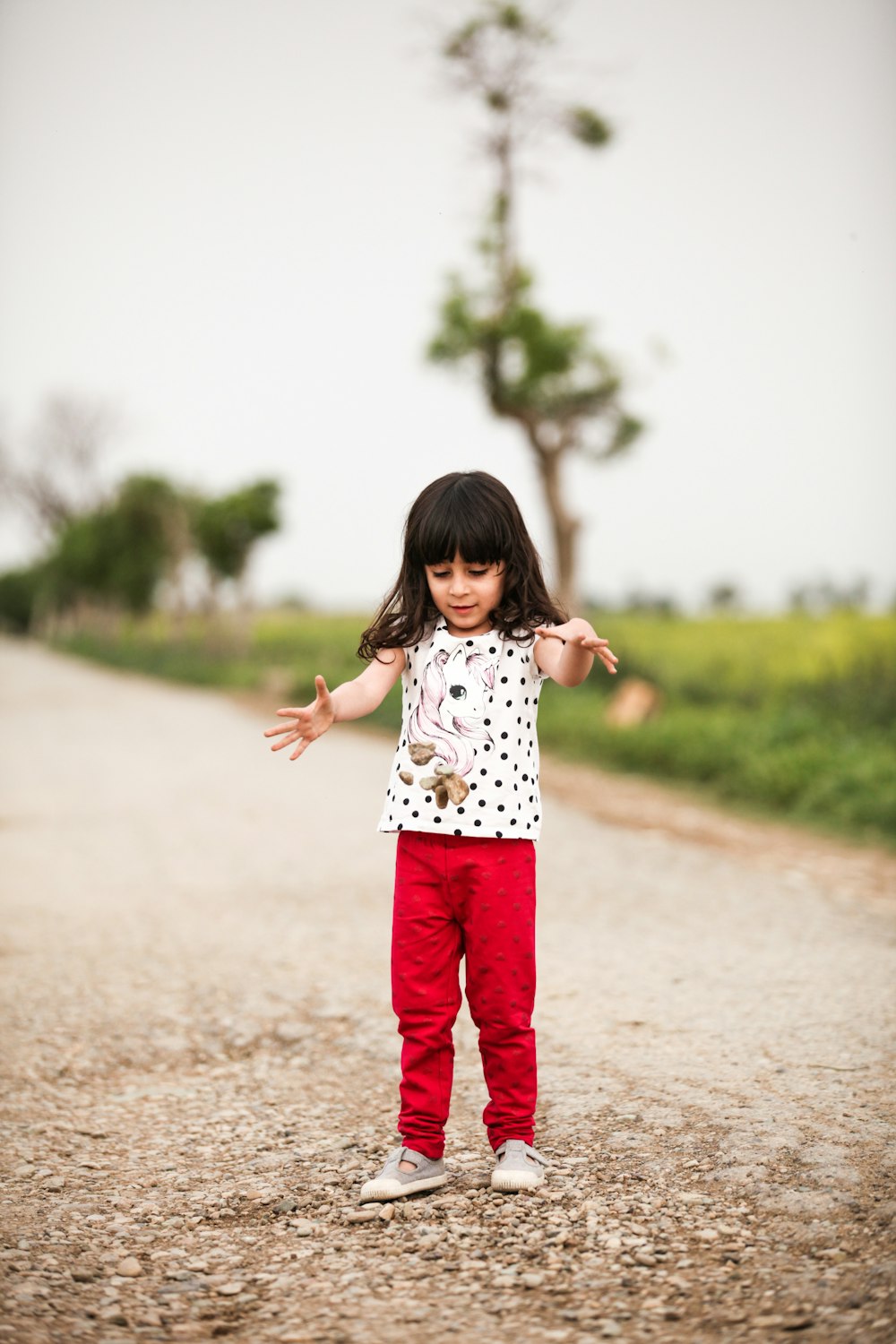 girl in white and red polka dot dress standing on gray sand during daytime