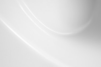 A smooth, white surface with soft shadows and gentle curves creating a subtle play of light and texture.