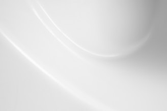 A smooth, white surface with soft shadows and gentle curves creating a subtle play of light and texture.