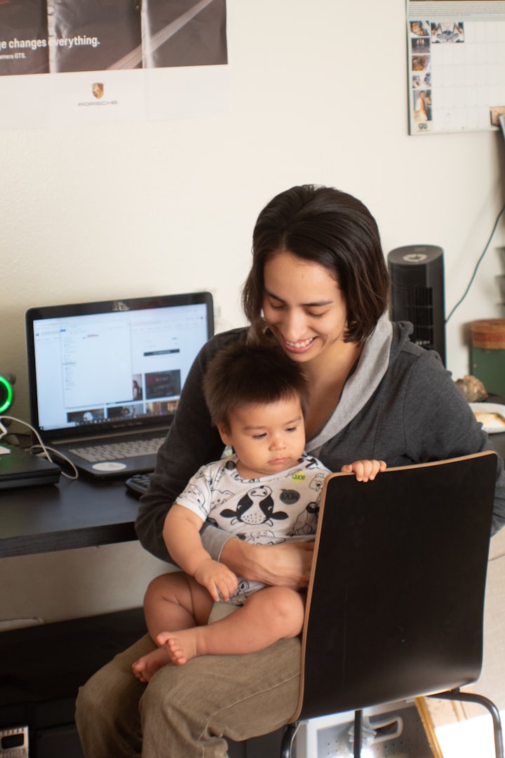 working mom sat at desk with son on her lap