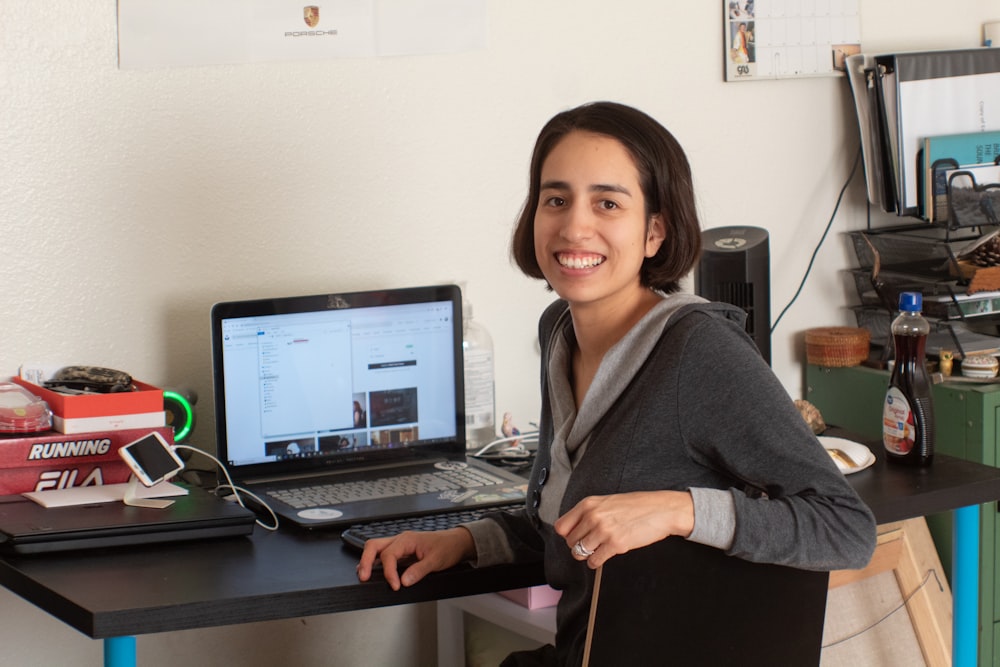 woman in gray long sleeve shirt sitting on chair in front of black laptop computer