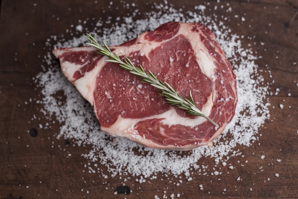 Perfectly seared steak being sliced on a cutting board with herbs and seasonings