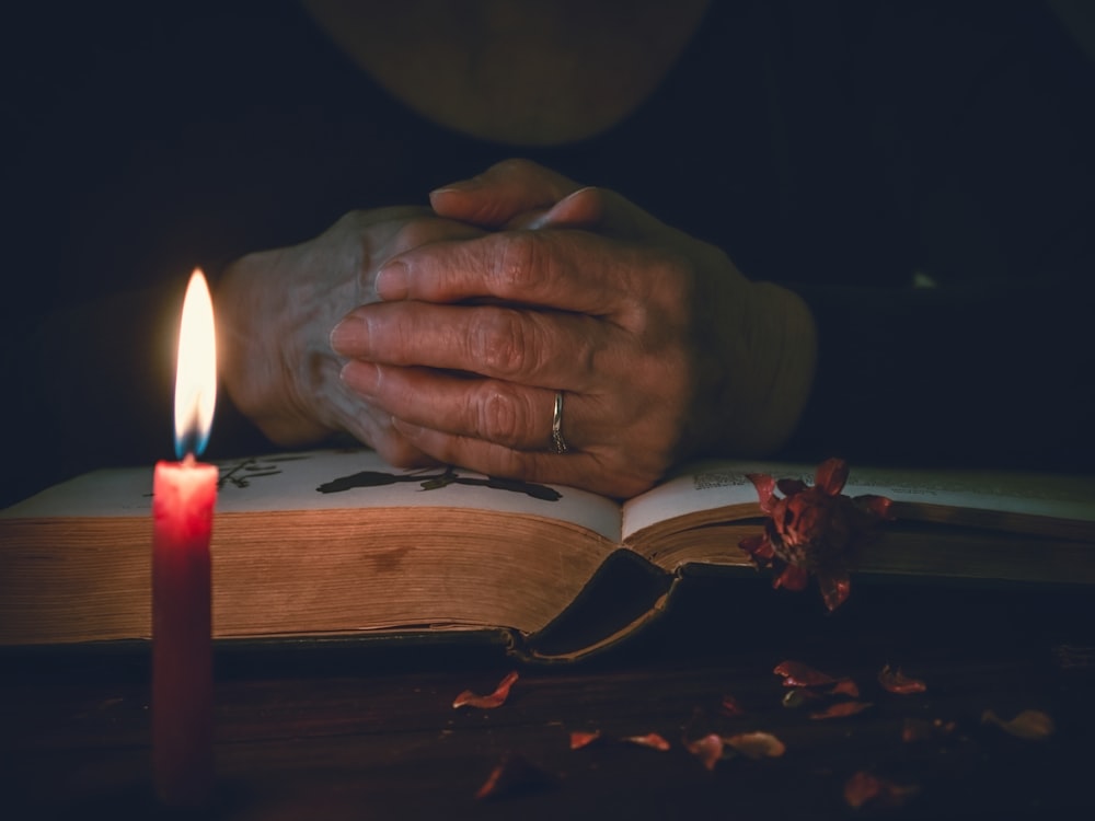 person holding lighted candle on brown wooden table