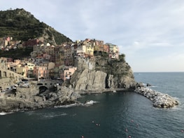 A scenic coastal village with colorful houses stacked on cliffs overlooking a calm sea.