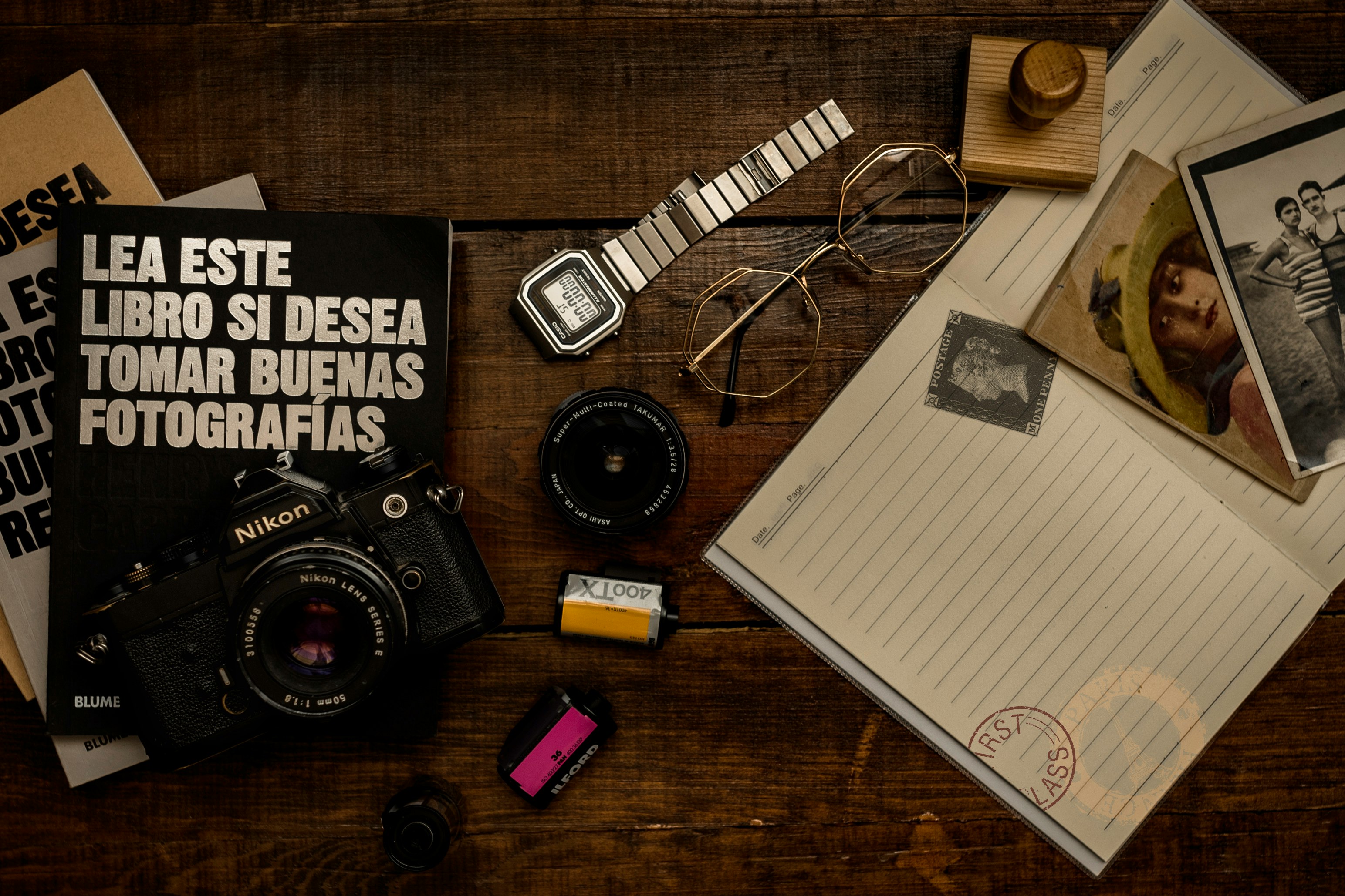 black and silver dslr camera beside white ruled paper on brown wooden table