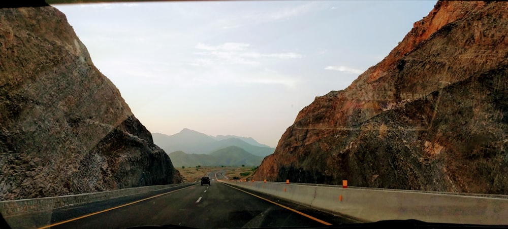 gray concrete road near brown mountain during daytime