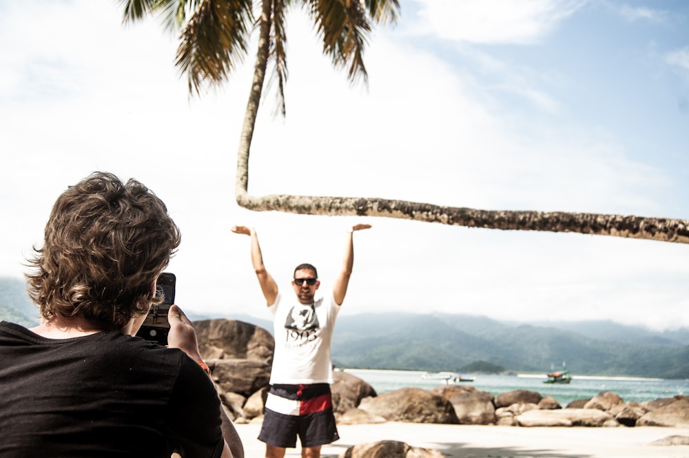 man in white crew neck t-shirt standing on beach shore during daytime