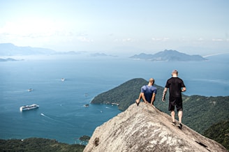 man in black shirt standing on rock formation near body of water during daytime