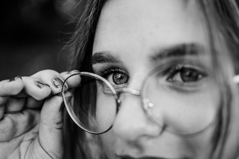 grayscale photo of woman holding magnifying glass